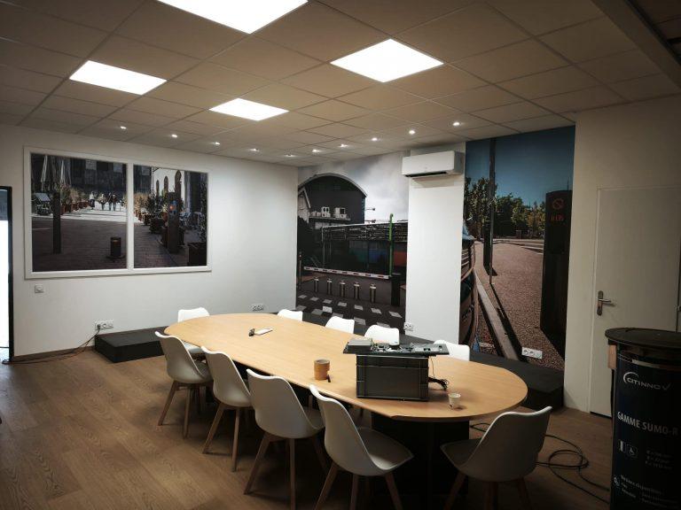 Salle de réunion moderne avec grande table ovale, chaises blanches et murs décorés de photos murales urbaines