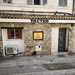 Façade d’un restaurant avec enseigne TASTER et panneau STREET FOOD CORNER, porte grise à droite