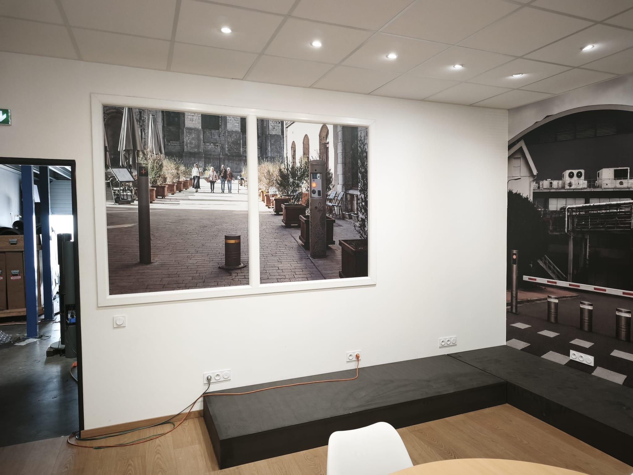 Salle intérieure avec deux grandes fresques murales représentant une cour pavée et une scène industrielle