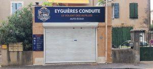 Façade d’une auto-école « Eyguières Conduite » avec rideau fermé et enseigne visible