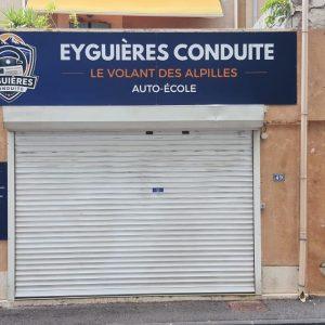 Façade d’une auto-école « Eyguières Conduite » avec rideau fermé et enseigne visible