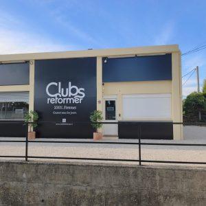 Façade beige du studio Clubs Reformer avec enseignes noires, vue de trois quarts