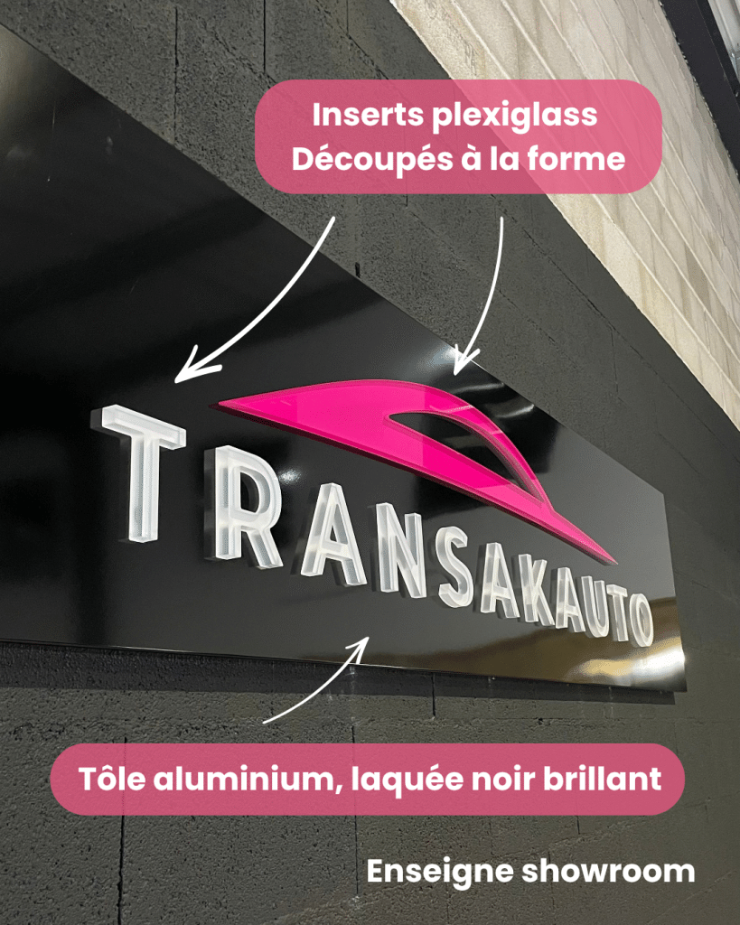 Enseigne showroom Transak Auto installée sur mur intérieur avec panneaux en tôle laquée et inserts plexiglas