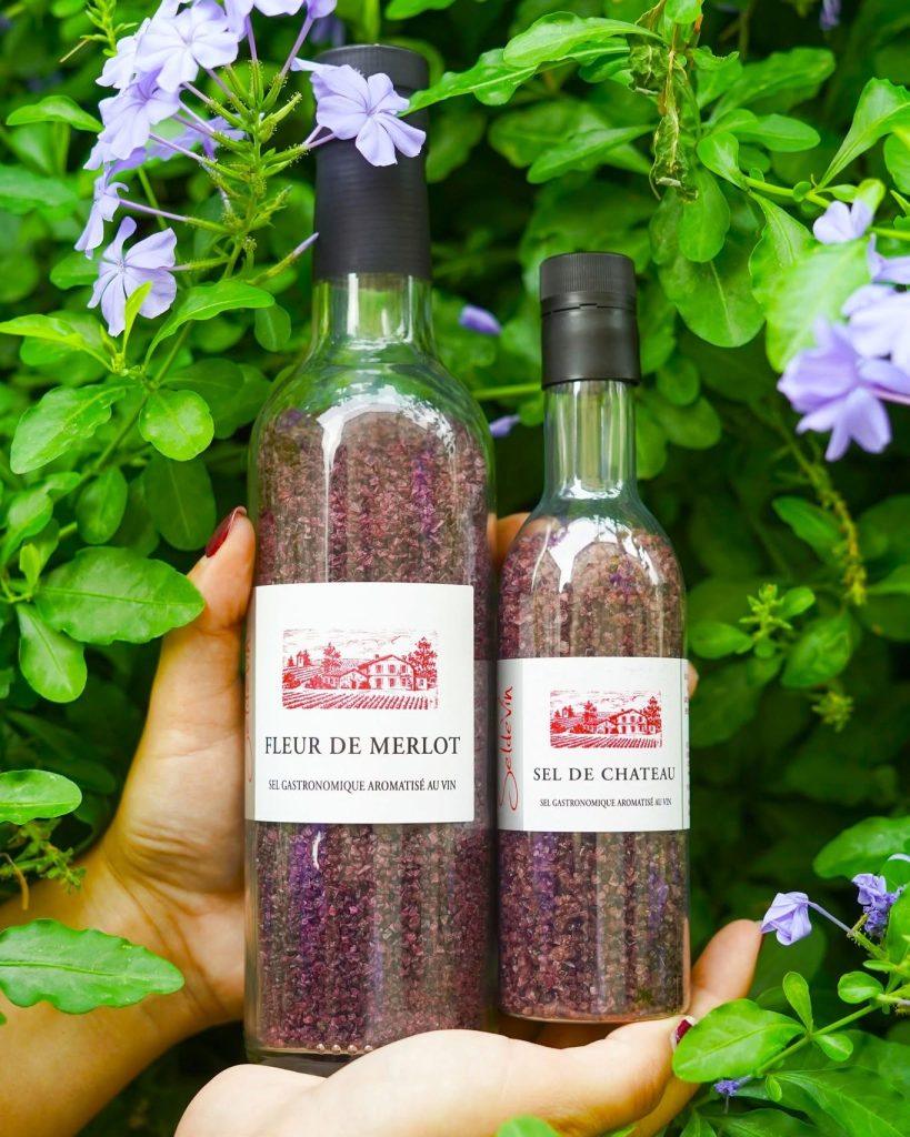 Deux bouteilles transparentes contenant sel violet étiquetées Fleur de Merlot et Sel de Chateau