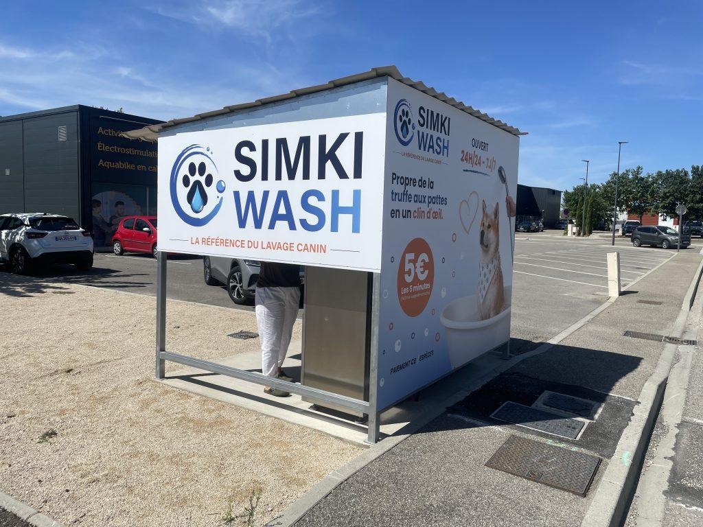 Box de lavage pour chiens Simki Wash habillé d'adhésifs imprimés sur un parking de station de lavage