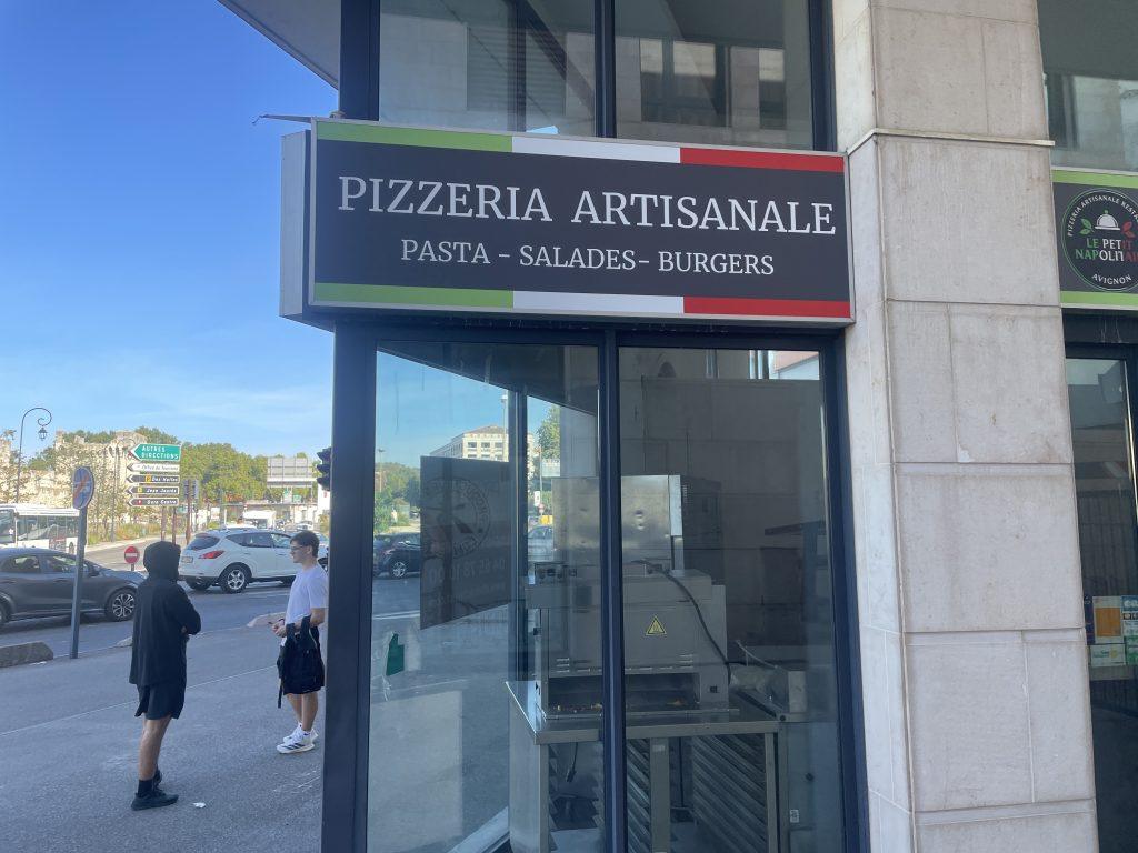 Bandeau 'Pizzeria Artisanale' installé en façade, angle de rue visible