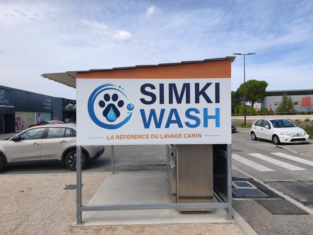 Panneau enseigne Simki Wash au logo patte de chien au-dessus d'une borne de lavage canin