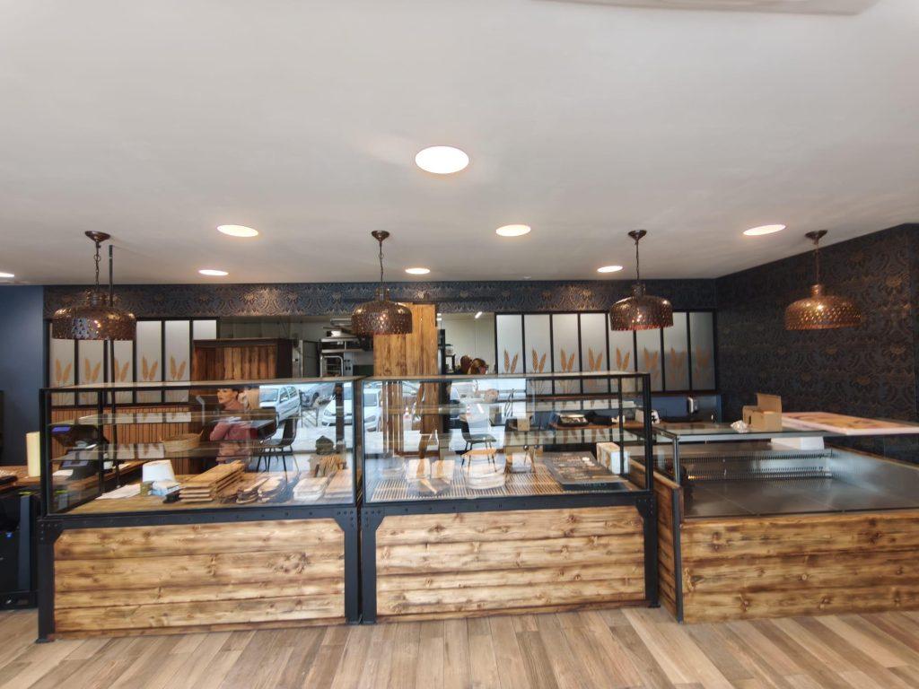 Comptoir de vente en bois et vitrines dans une boulangerie au mur bleu décoré