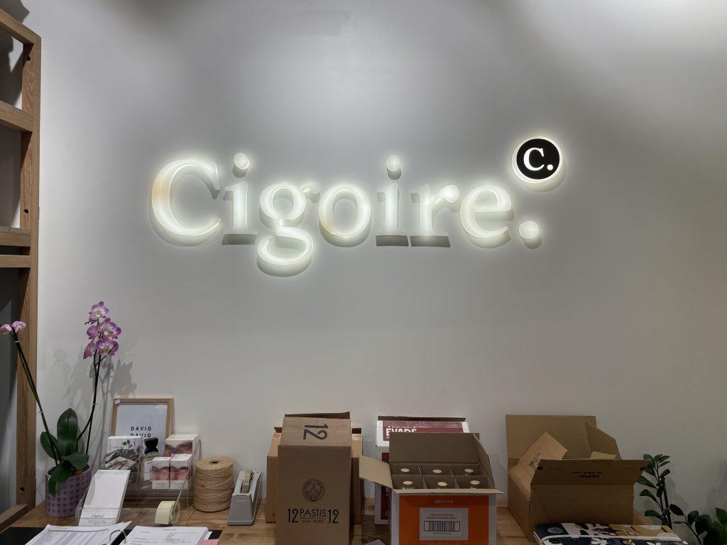 Enseigne lumineuse murale « Cigoire » rétro éclairée avec badge rond 'C.' visible depuis le comptoir