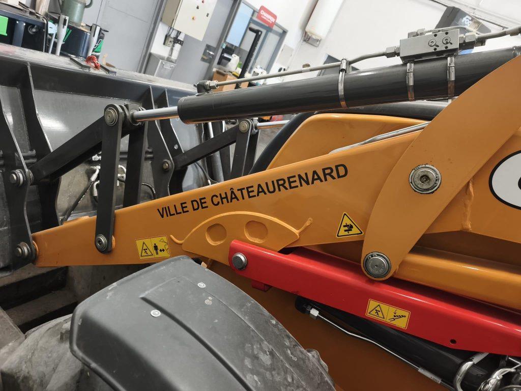 Bras de chargeuse orange avec marquage Ville de Châteaurenard