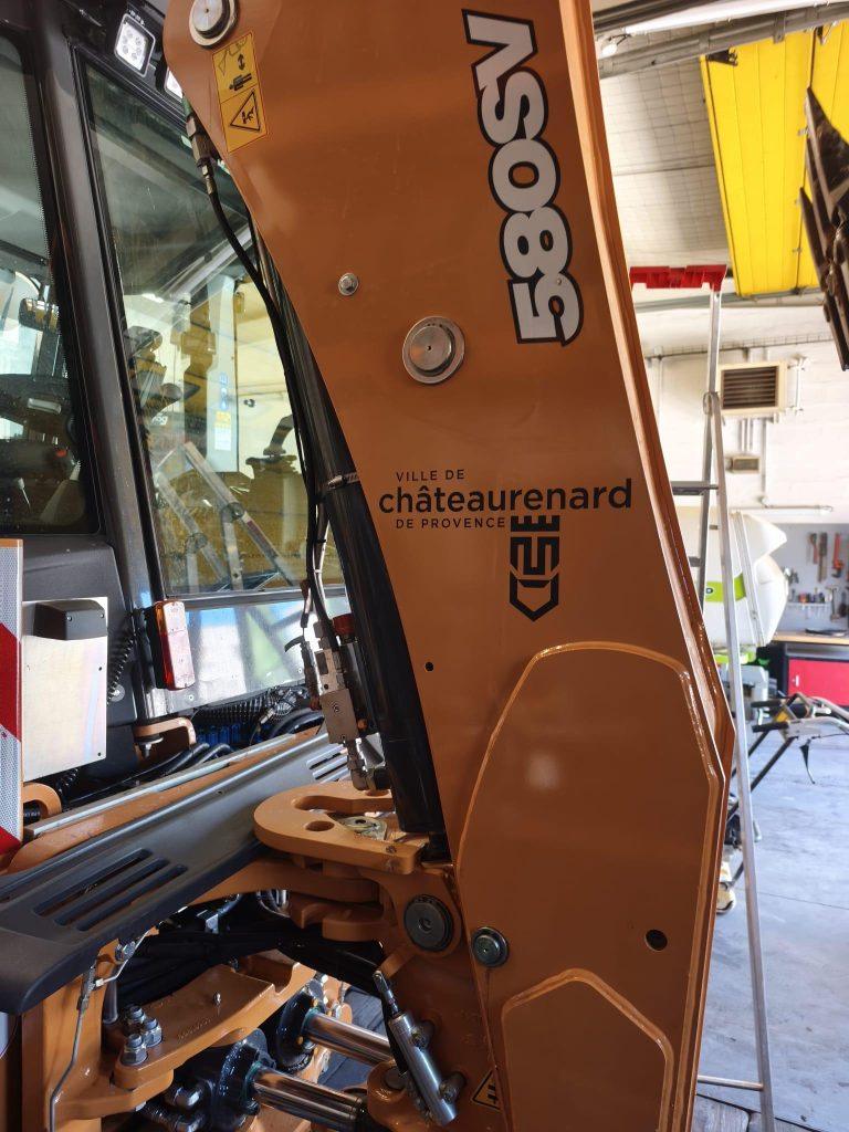 Logo Ville de Châteaurenard posé sur le bras d'un tractopelle Case 580SV